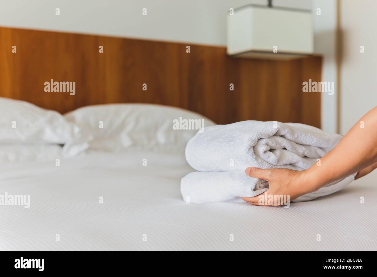 Mains mettant des serviettes de bain blanches fraîches sur le drap de lit. Banque D'Images