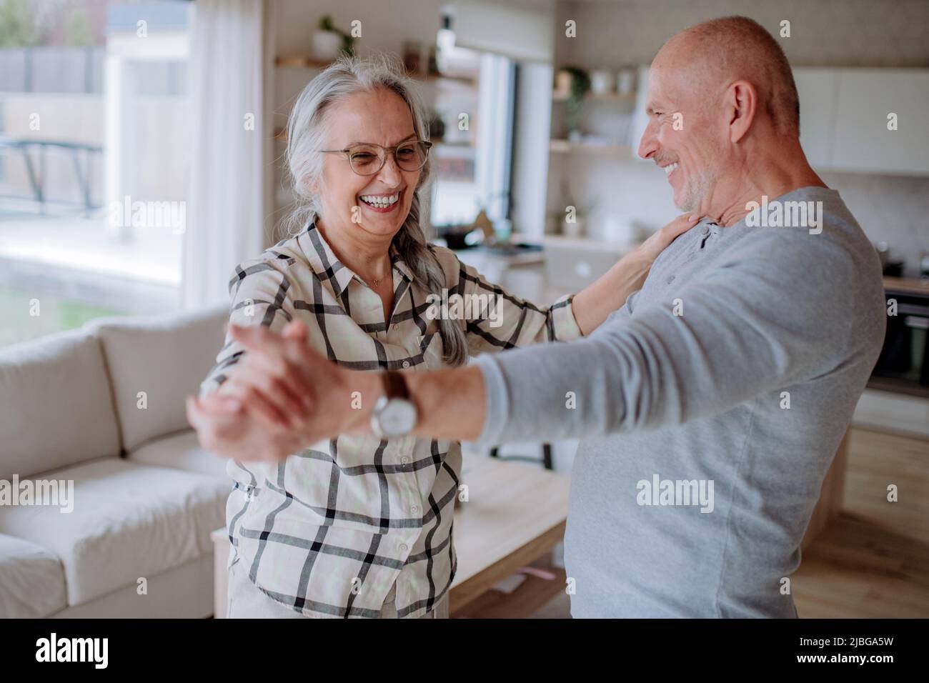 Couple senior joyeux dansant ensemble à la maison. Banque D'Images