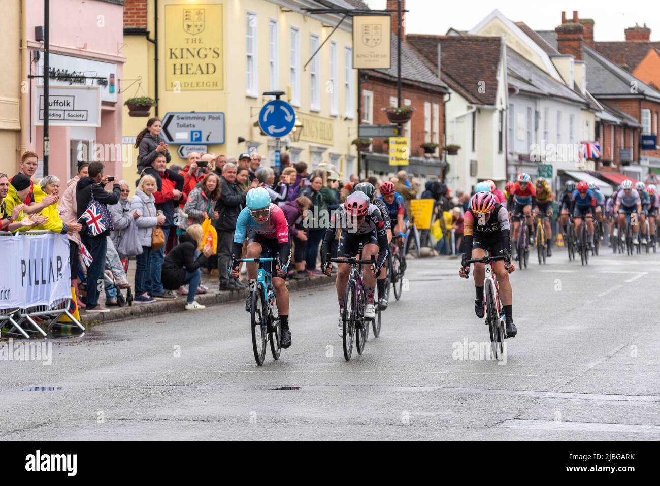 High Street, Hadleigh, Suffolk, Royaume-Uni. 6th juin 2022. La course cycliste UCI Women’s Tour a commencé avec les meilleurs pilotes du monde au départ de Colchester pour la phase 1 142km à travers la campagne Essex et Suffolk jusqu’à la fin à Bury St. Edmunds. Une section de sprint s'est terminée dans la haute rue d'Hadleigh sous la pluie, gagnée par Maike van der Duin du Col Wahoo (à gauche), devant Alison Jackson et Laura Tomasi. Des spectateurs ont bordé la rue pour encourager les coureurs Banque D'Images High Street, Hadleigh, Suffolk, Royaume-Uni. 6th juin 2022. La course cycliste UCI Women’s Tour a commencé avec les meilleurs pilotes du monde au départ de Colchester pour la phase 1 142km à travers la campagne Essex et Suffolk jusqu’à la fin à Bury St. Edmunds. Une section de sprint s'est terminée dans la haute rue d'Hadleigh sous la pluie, gagnée par Maike van der Duin du Col Wahoo (à gauche), devant Alison Jackson et Laura Tomasi. Des spectateurs ont bordé la rue pour encourager les coureurs Banque D'Images