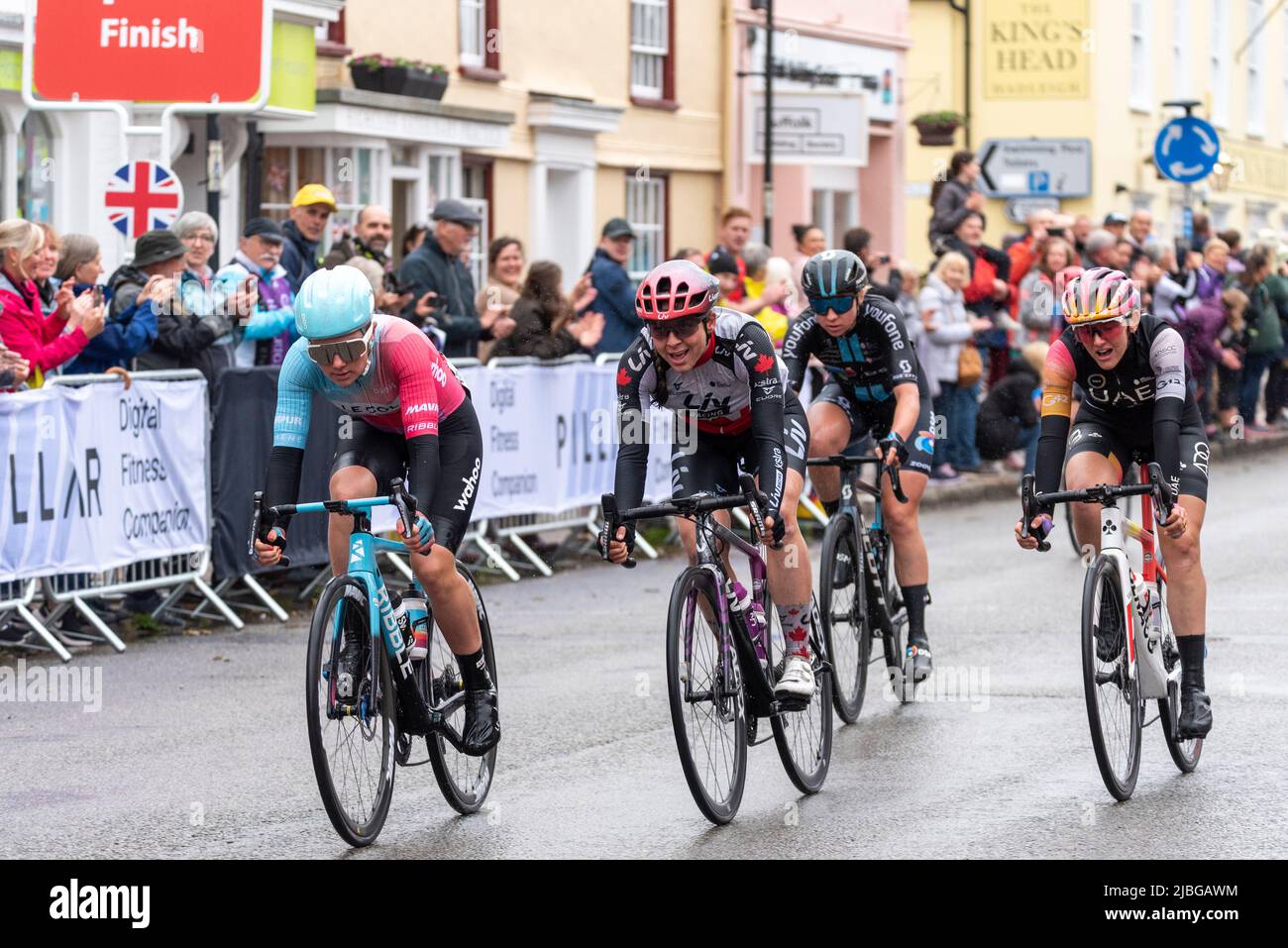 High Street, Hadleigh, Suffolk, Royaume-Uni. 6th juin 2022. La course cycliste UCI Women’s Tour a commencé avec les meilleurs pilotes du monde au départ de Colchester pour la phase 1 142km à travers la campagne Essex et Suffolk jusqu’à la fin à Bury St. Edmunds. Une section de sprint s'est terminée dans la haute rue d'Hadleigh sous la pluie, gagnée par Maike van der Duin du Col Wahoo (à gauche), devant Alison Jackson et Laura Tomasi. Des spectateurs ont bordé la rue pour encourager les coureurs Banque D'Images High Street, Hadleigh, Suffolk, Royaume-Uni. 6th juin 2022. La course cycliste UCI Women’s Tour a commencé avec les meilleurs pilotes du monde au départ de Colchester pour la phase 1 142km à travers la campagne Essex et Suffolk jusqu’à la fin à Bury St. Edmunds. Une section de sprint s'est terminée dans la haute rue d'Hadleigh sous la pluie, gagnée par Maike van der Duin du Col Wahoo (à gauche), devant Alison Jackson et Laura Tomasi. Des spectateurs ont bordé la rue pour encourager les coureurs Banque D'Images