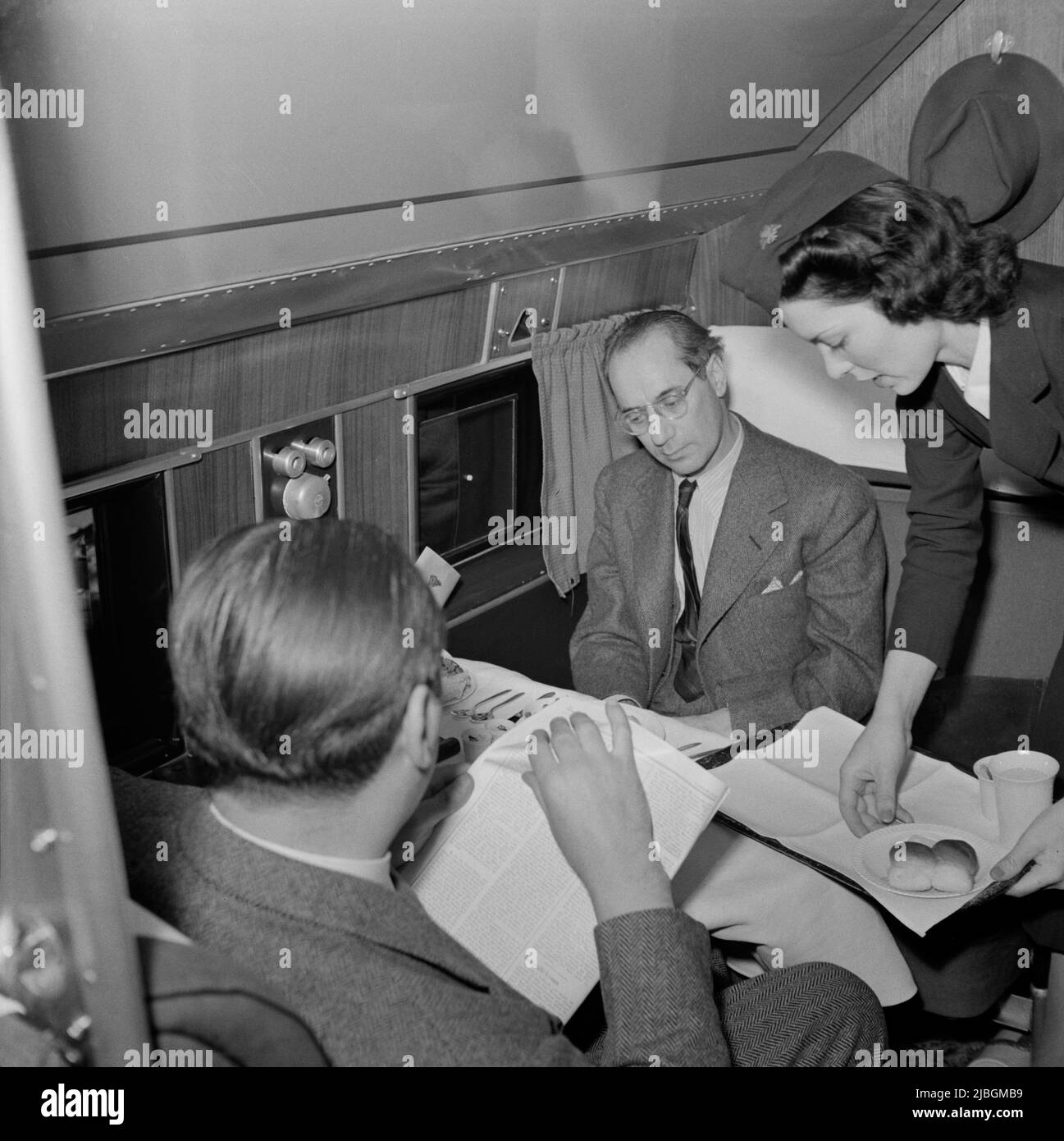 Photo vintage vers 1941 d'un agent de bord qui cherche à servir de la nourriture et des boissons aux passagers voyageant dans un avion de ligne Douglas DC3 en vol de Washington DC à Los Angeles Banque D'Images