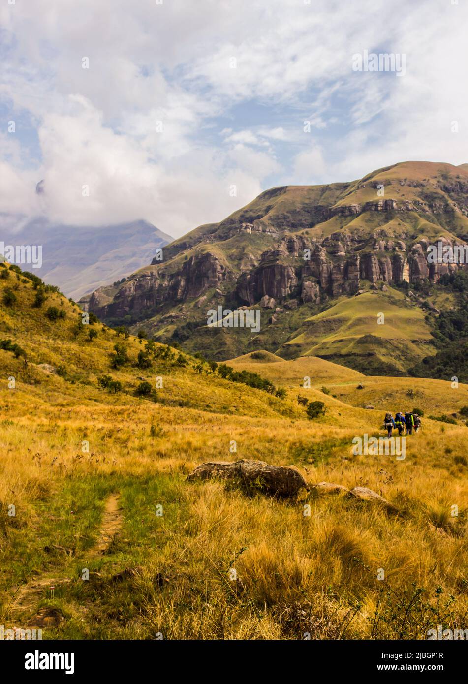 Randonneurs marchant dans les montagnes du Drakensberg avec les hauts sommets en arrière-plan enveloppés dans des nuages bas Banque D'Images