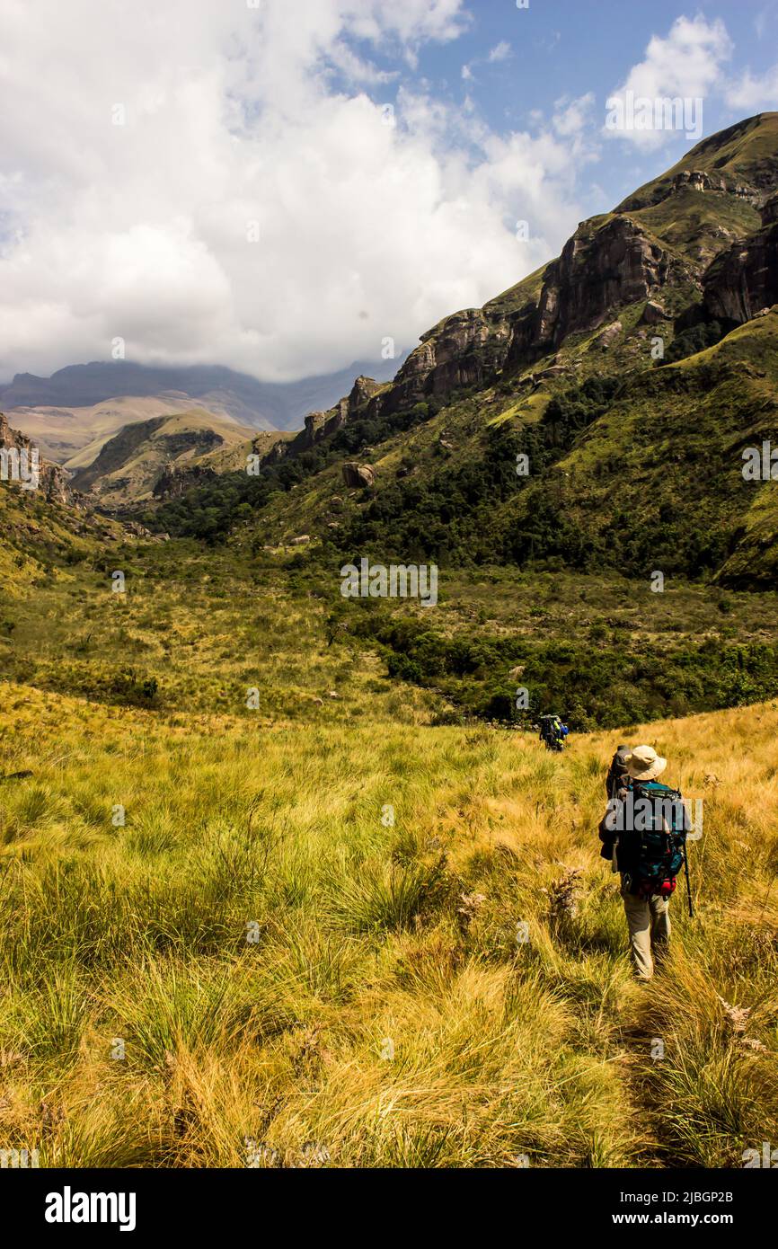 Randonneurs marchant dans les montagnes du Drakensberg avec les hauts sommets en arrière-plan enveloppés dans des nuages bas Banque D'Images