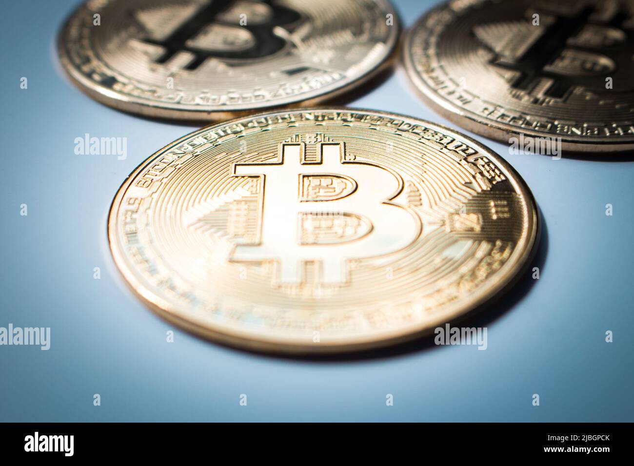 Gros plan de trois bitcoins d'or sur fond plat. Banque D'Images