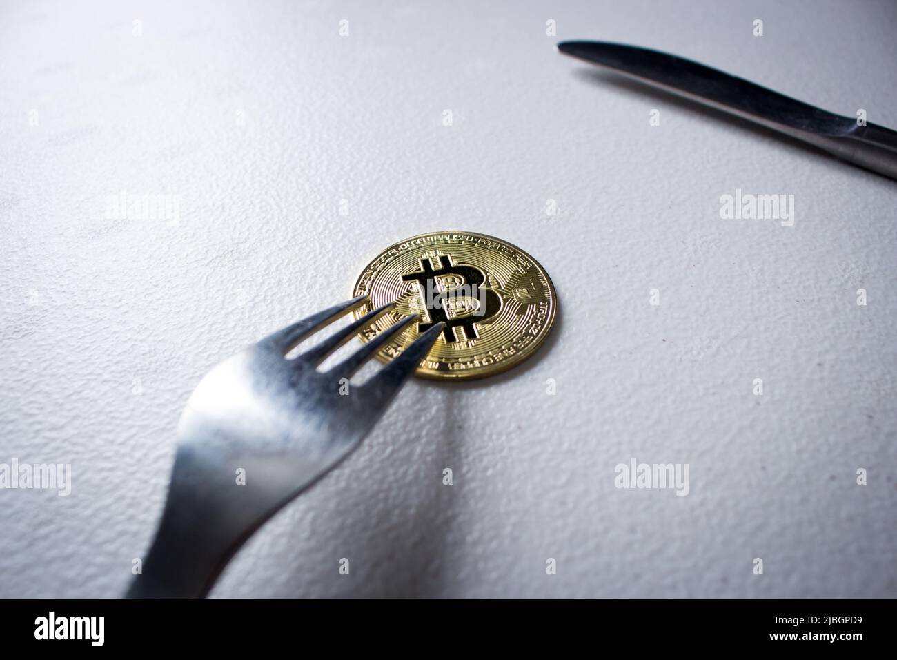 Image concept de la fourche dure Bitcoin (chaîne de blocs). La fourchette d'argent est un bitcoin doré. La pièce de monnaie crypto-monnaie sous la fourchette est sur la table dans l'obscurité. Banque D'Images