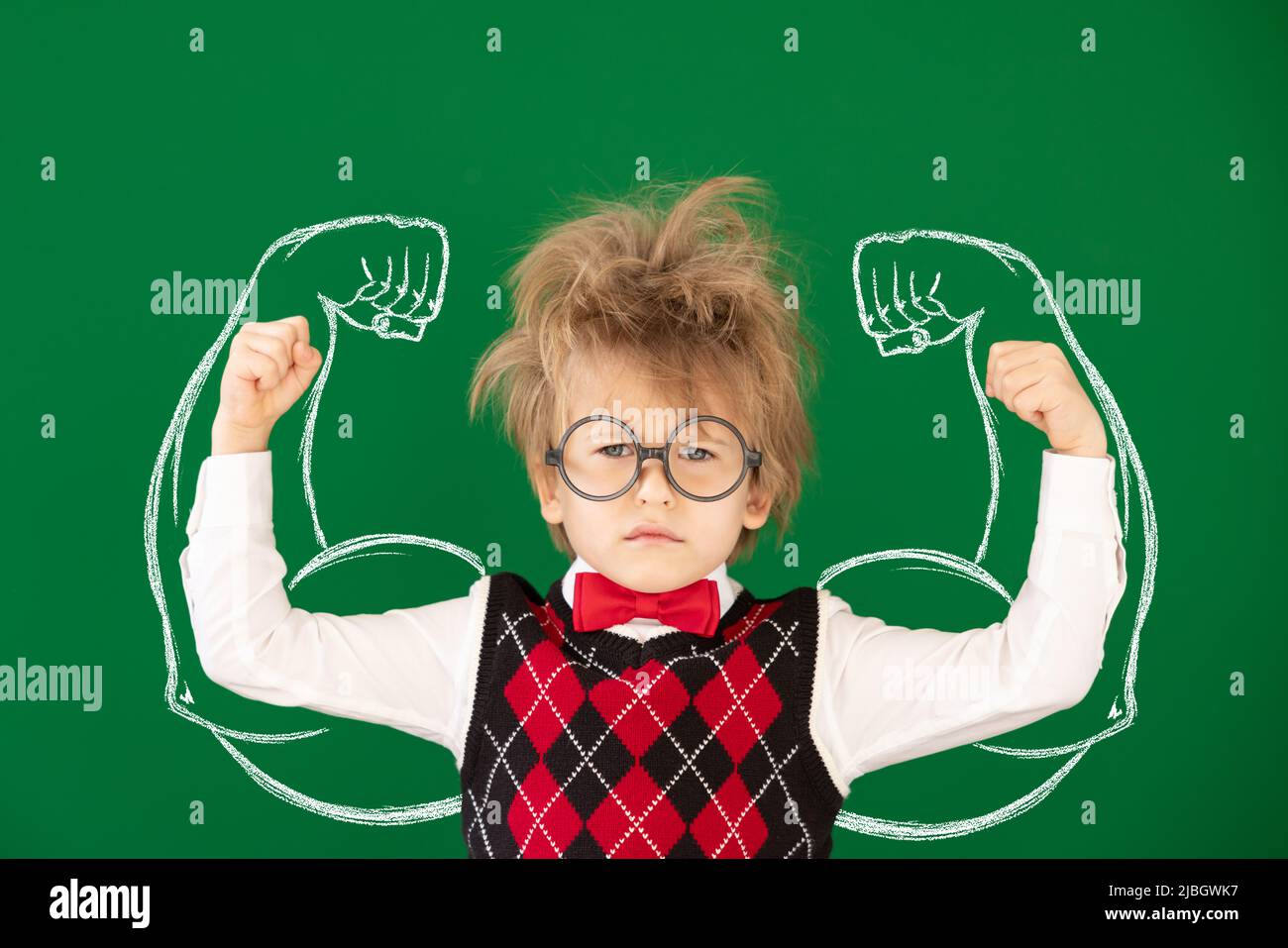 Drôle d'enfant étudiant en classe. Un enfant heureux contre un tableau noir vert. Concept d'éducation. Retour à l'école Banque D'Images