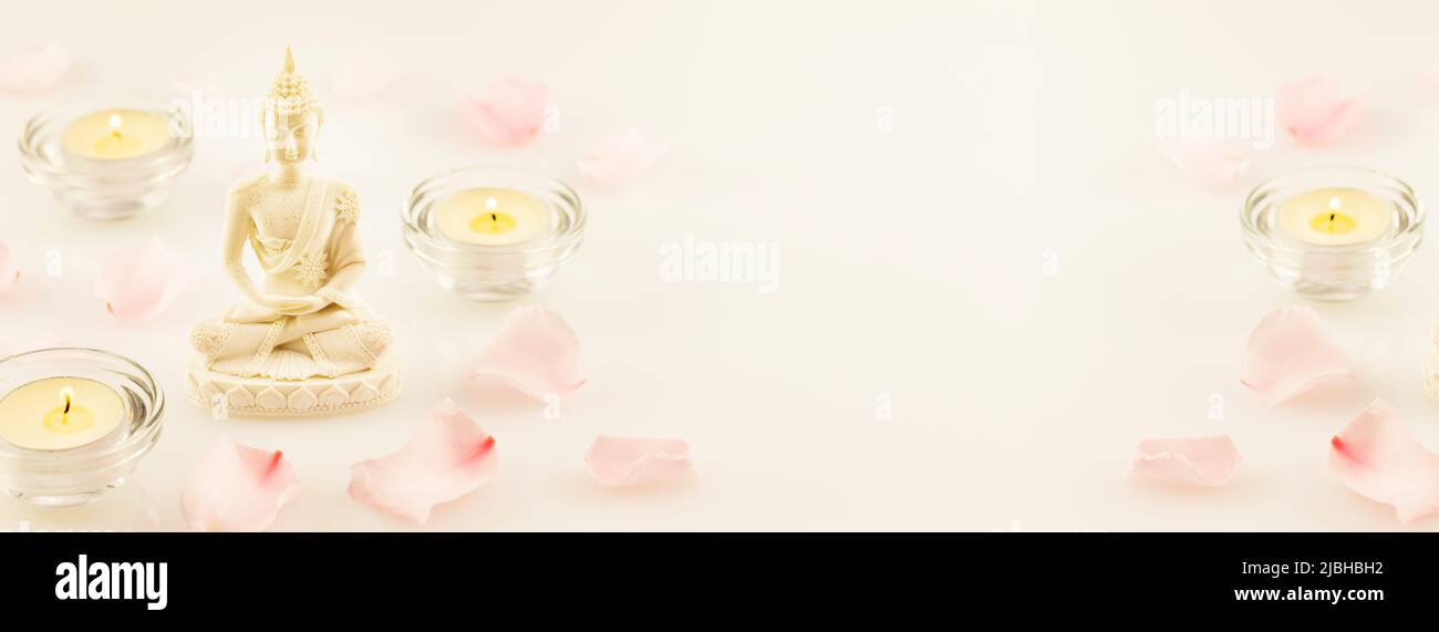 Bannière de vacances bouddhiste avec statue de bouddha, pétales de rose et bougies Banque D'Images