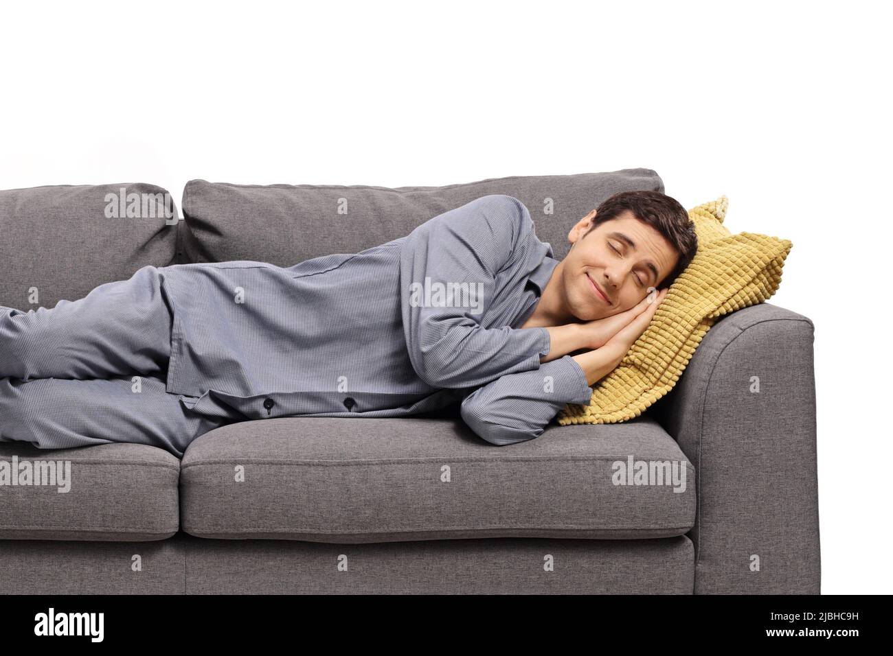 Homme heureux en pyjama dormant sur un canapé et rêvant isolé sur fond blanc Banque D'Images