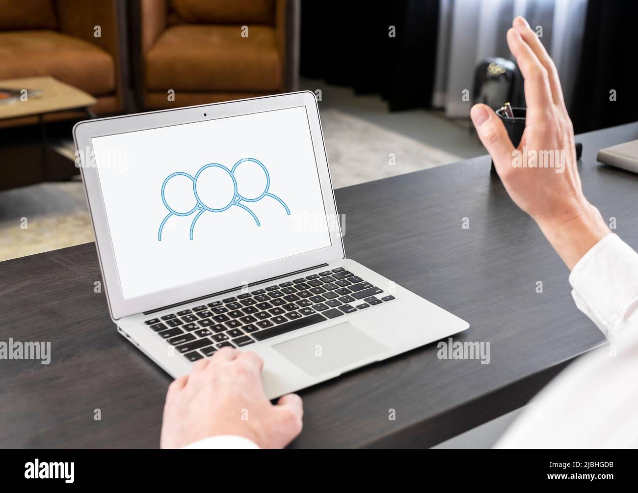 Conférences virtuelles. Homme d'affaires accueillant des partenaires à la main, parlant par vidéoconférence, organisant des réunions d'affaires en ligne. Concept de travail à distance. Homme assis à une table avec un ordinateur portable. Photo de haute qualité Banque D'Images