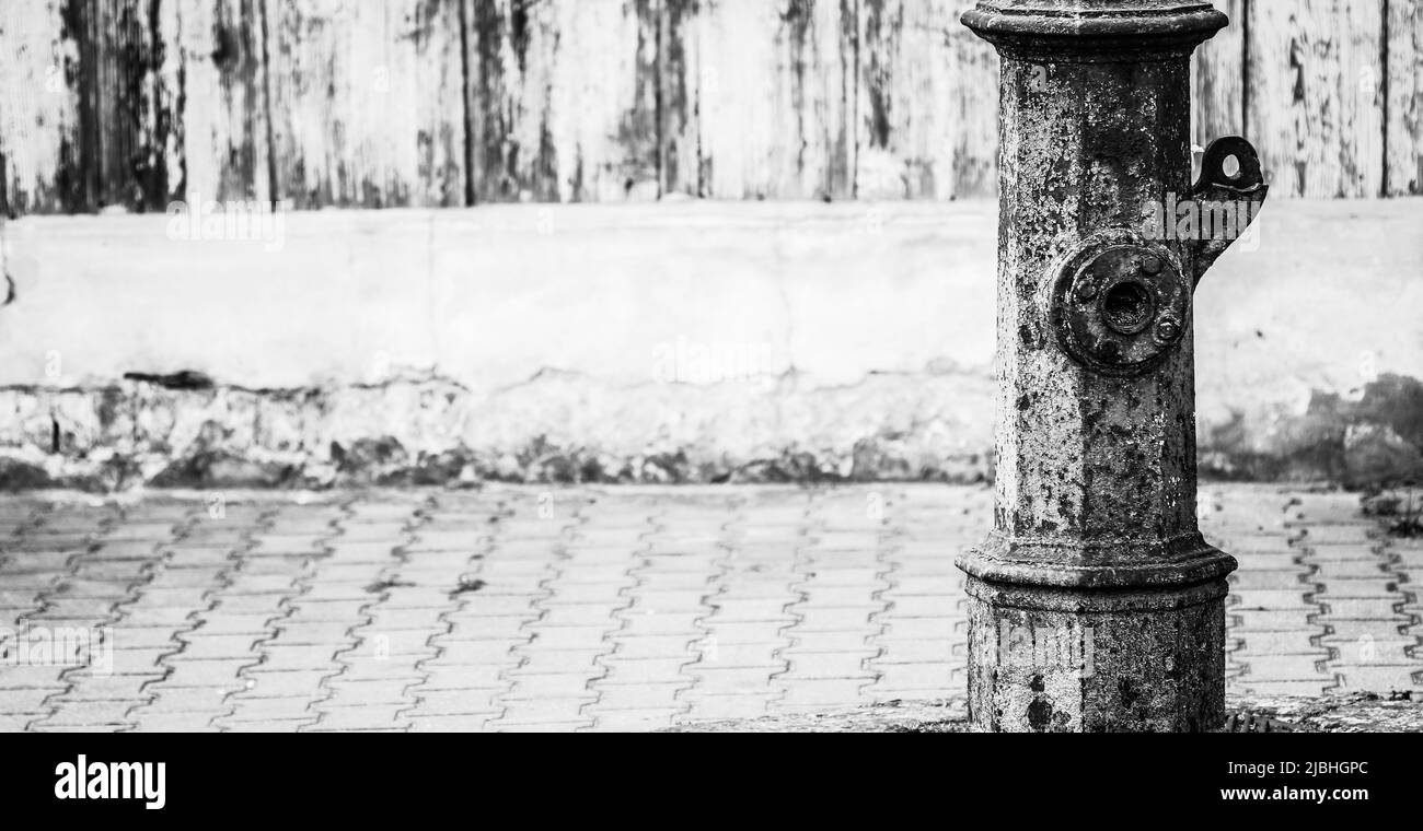 Très vieux avertissement vert hors service pompe à eau de rue debout le long de la chaussée avec espace de copie, image noir et blanc Banque D'Images