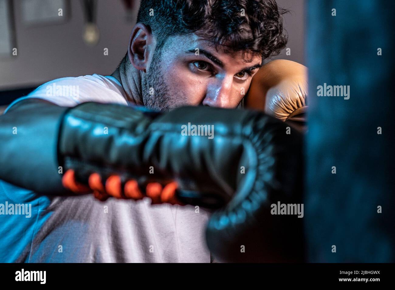 Un jeune boxeur caucasien frappe le sac avec des gants de boxe Banque D'Images