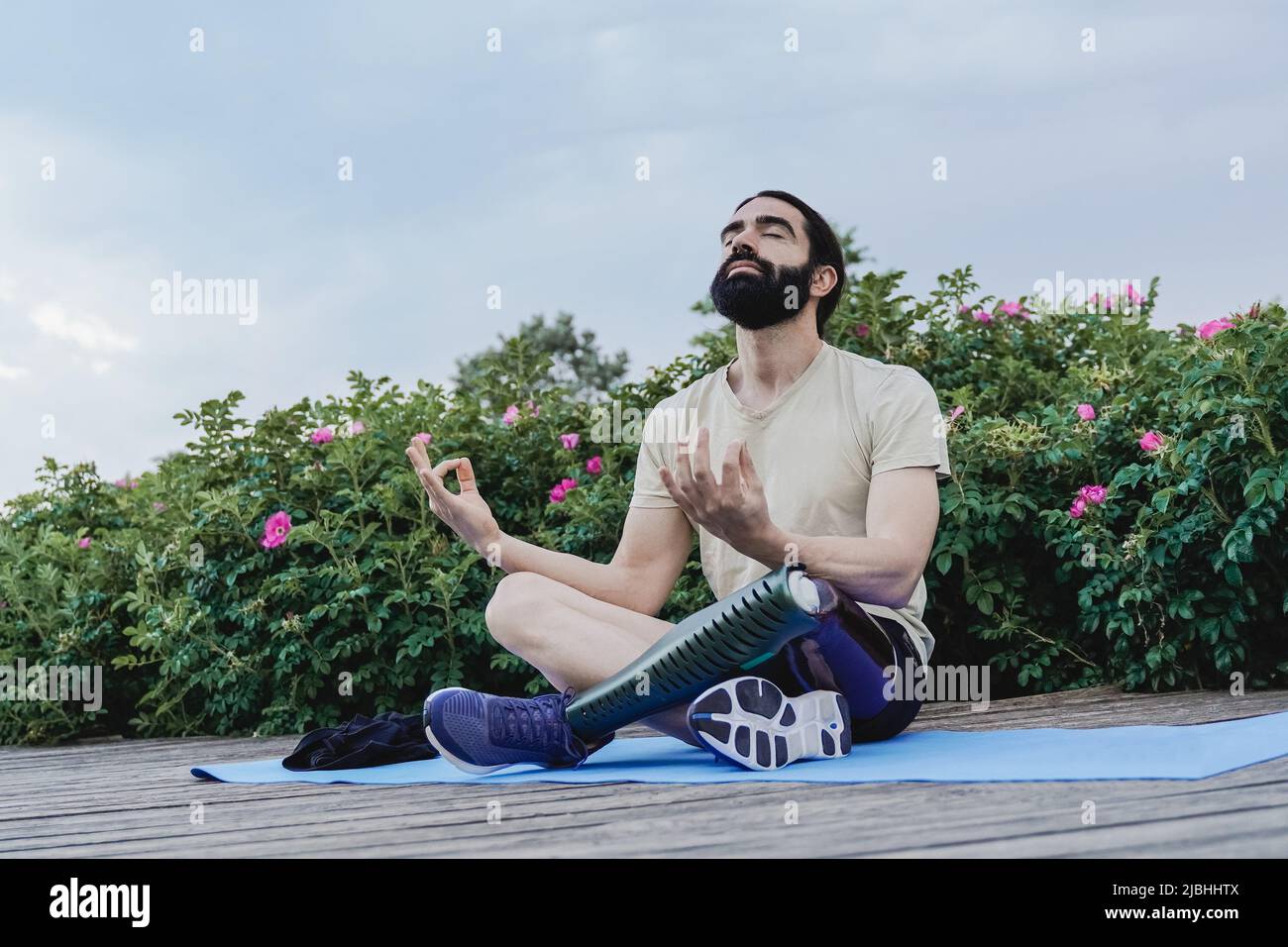 Jeune homme avec une jambe prothétique faisant de la méditation en plein air au parc de la ville - Focus sur le visage Banque D'Images