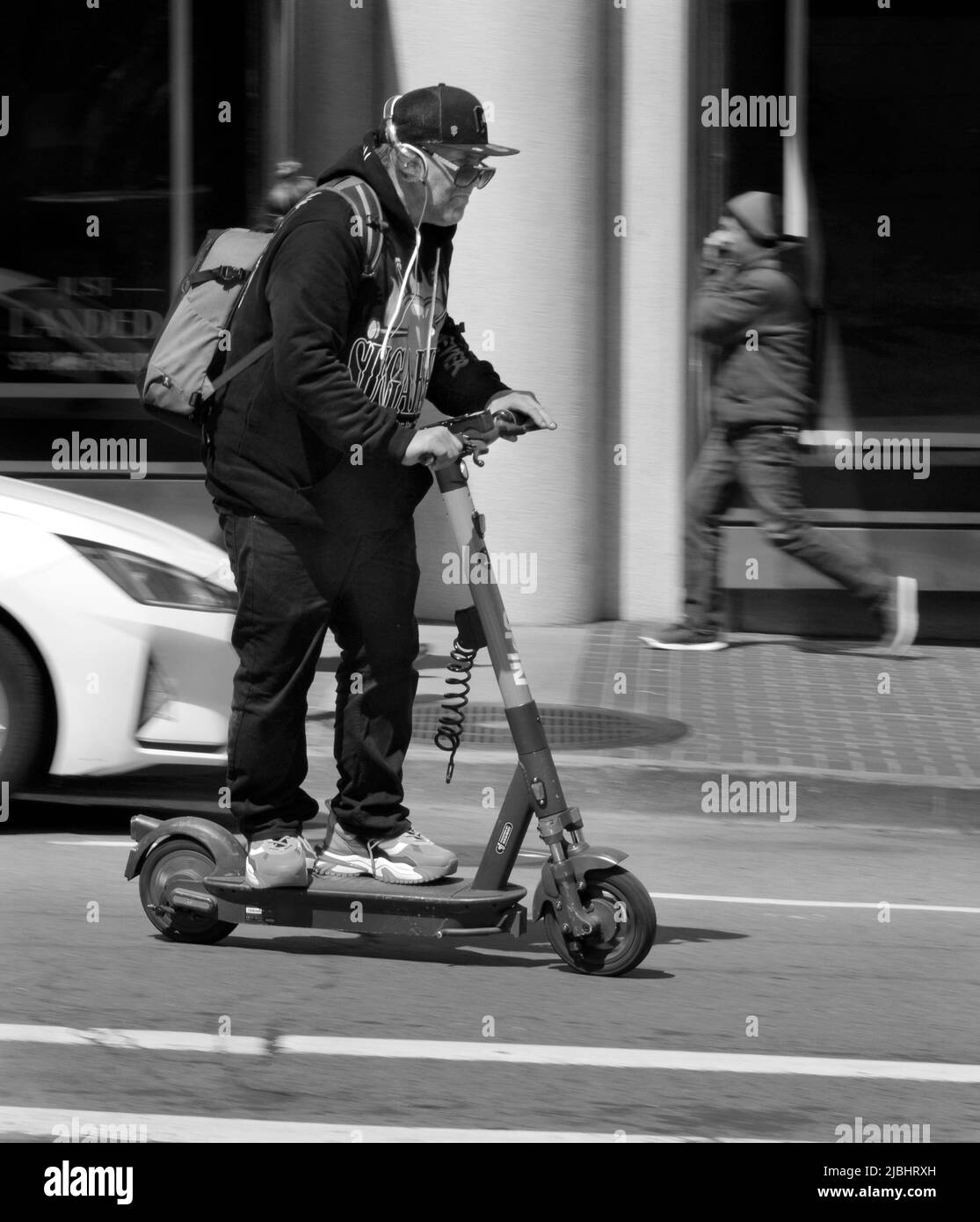 Un homme voyage le long d'une rue animée de San Francisco, Californie, sur un scooter électrique alimenté par batterie. Banque D'Images