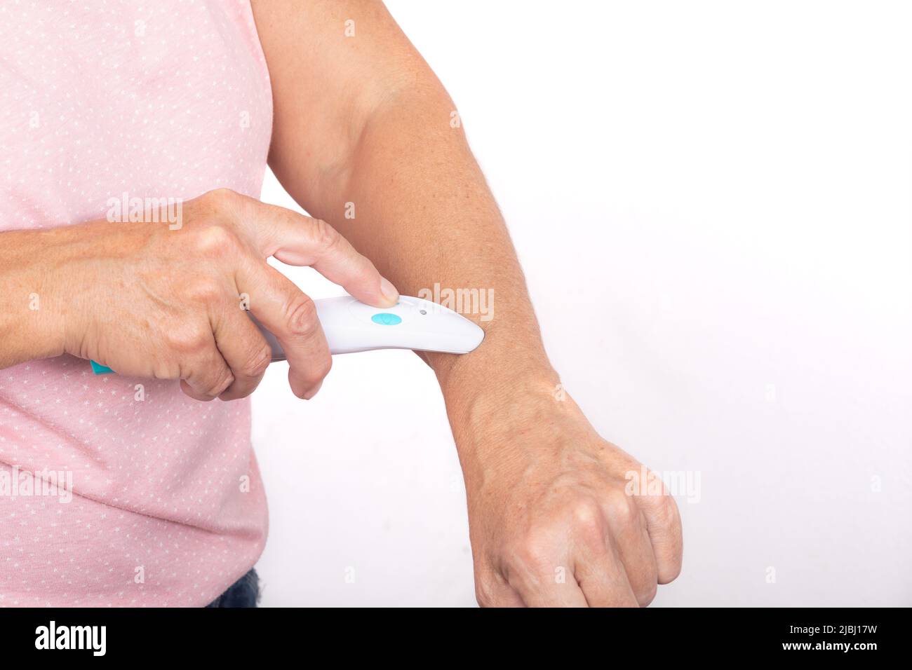 Une femme traite une piqûre de moustique sur son bras avec un guérisseur électrique - isolé sur fond blanc. Banque D'Images