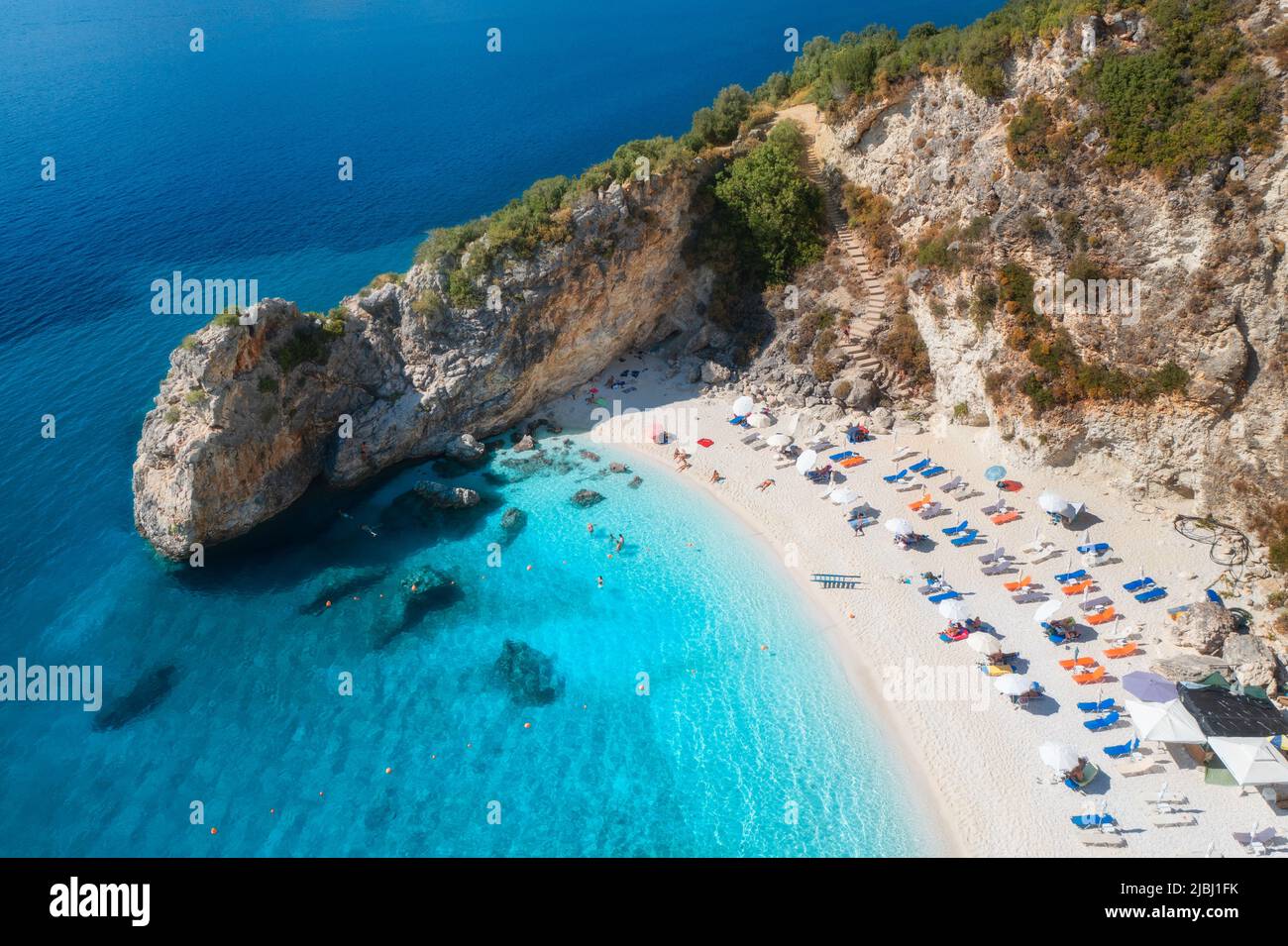 Vue aérienne sur la mer bleue, la roche, la plage de sable avec parasols Banque D'Images