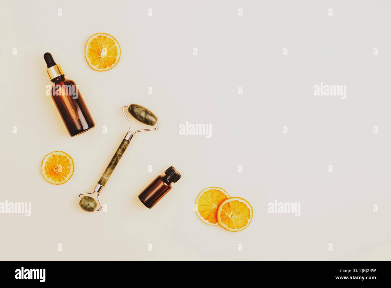 Accessoires cosmétiques, outils pour le traitement de beauté cosmétique anti-âge sur fond beige neutre avec tranches d'orange séchées. Vue de dessus, Flat lay, copie sp Banque D'Images