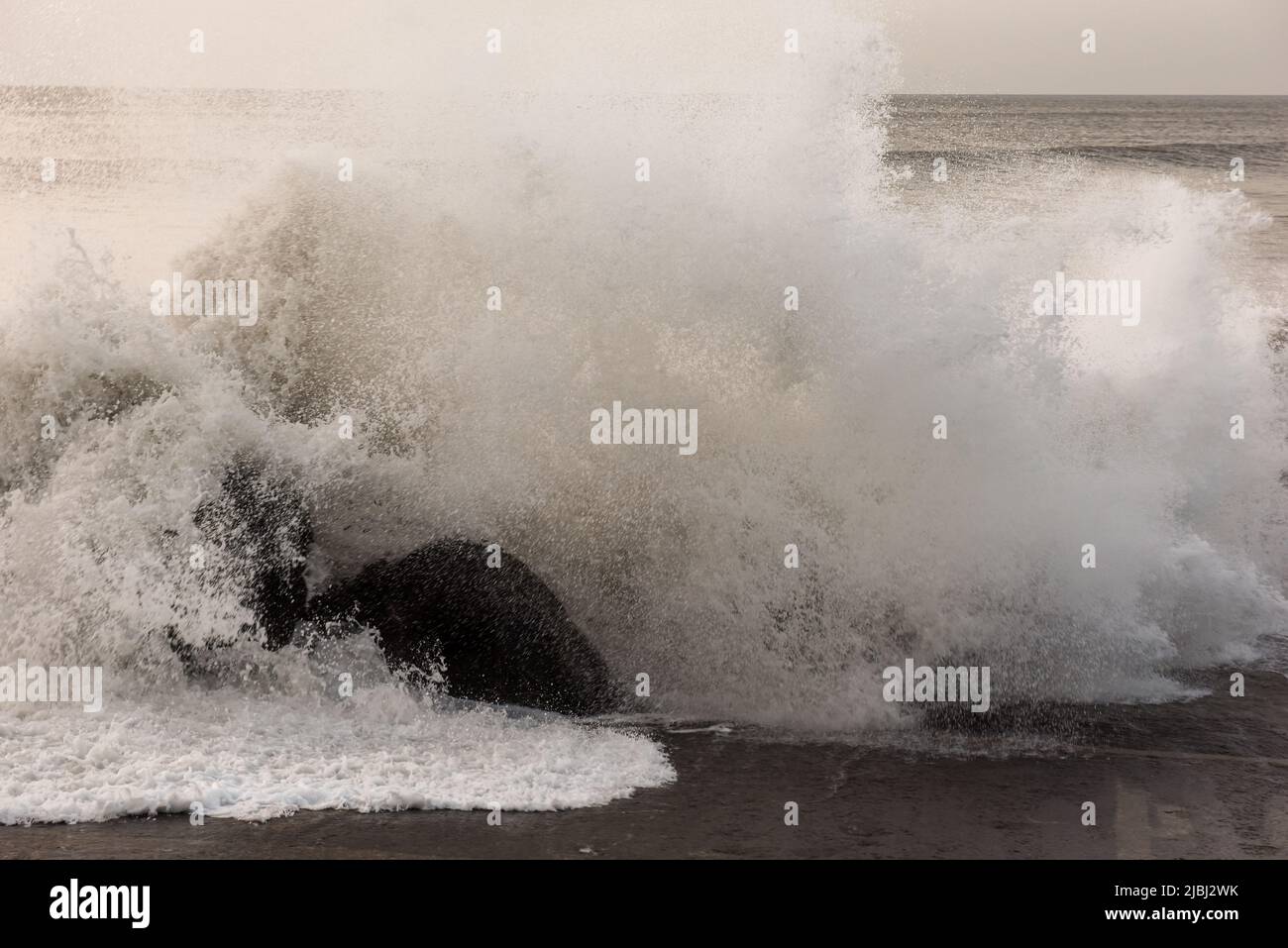 Des vagues qui se brisent et qui se brisent au-dessus de rochers sur la rive de la mer Banque D'Images