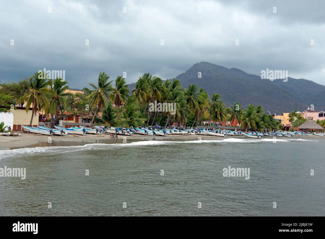 Vue panoramique sur les bateaux de pêche sur la plage avec des palmiers et des collines à Zihuatanejo, Mexique Banque D'Images