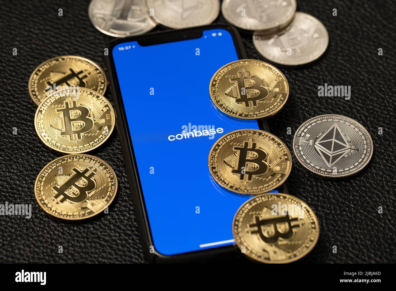 Bolzano, Italie - 10 avril. 2021: Application Coinbase sur smartphone à côté de bitcoin et de pièces de monnaie éthérée sur fond de cuir Banque D'Images