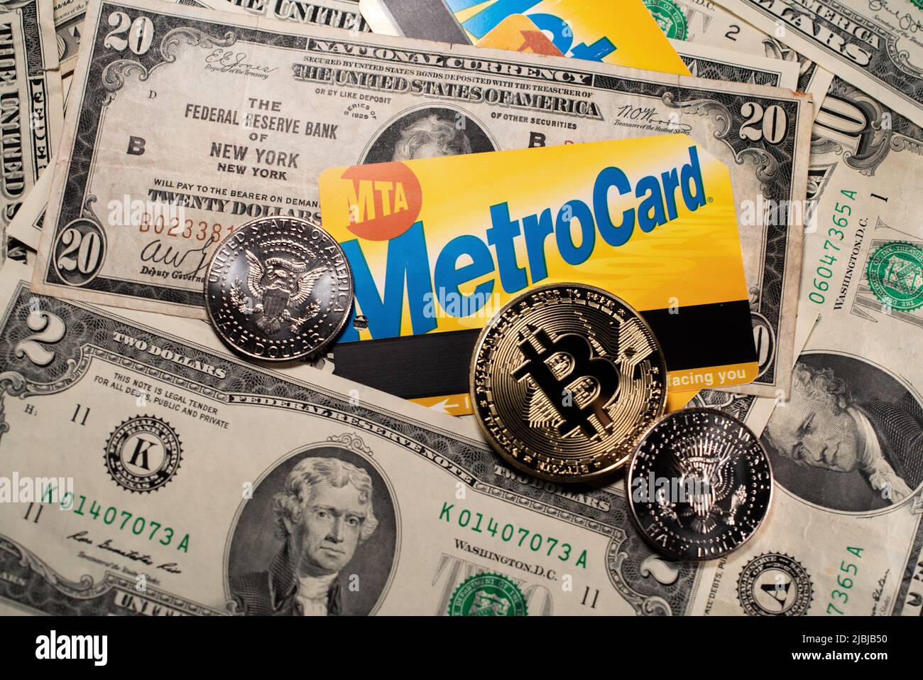 Manhattan, New York/Etats-Unis - 26 mars. 2021: Bitcoin sur la carte de métro NYC et les billets en dollars et les pièces de la moitié du dollar. Achat de billet de transport public avec Banque D'Images