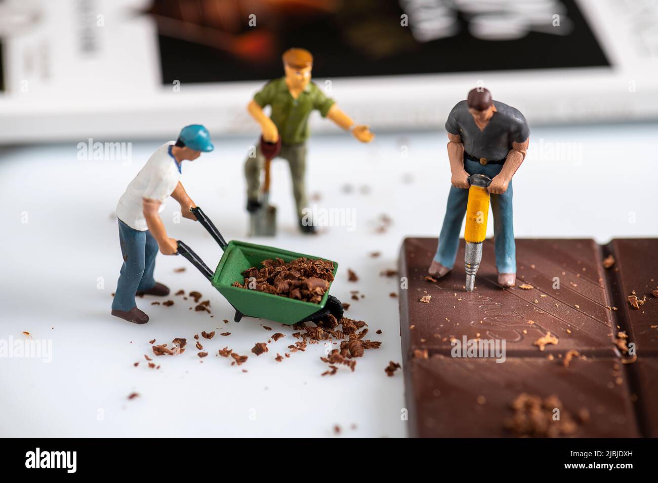 Miniature personnes petit modèle de figure humaine écrivant le mot chocolat Banque D'Images