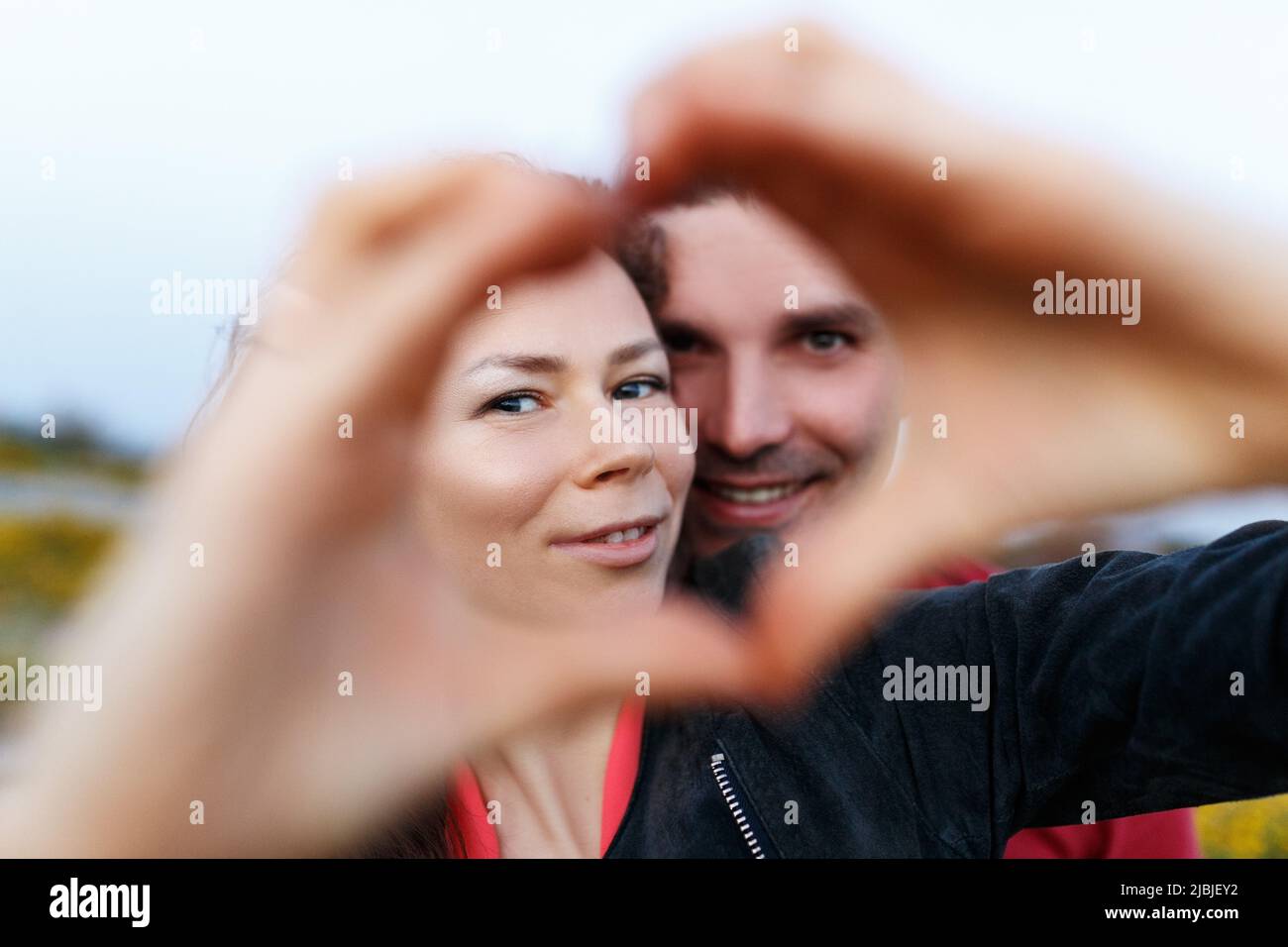 Couple d'âge moyen souriant et faisant le cœur avec les mains. Banque D'Images