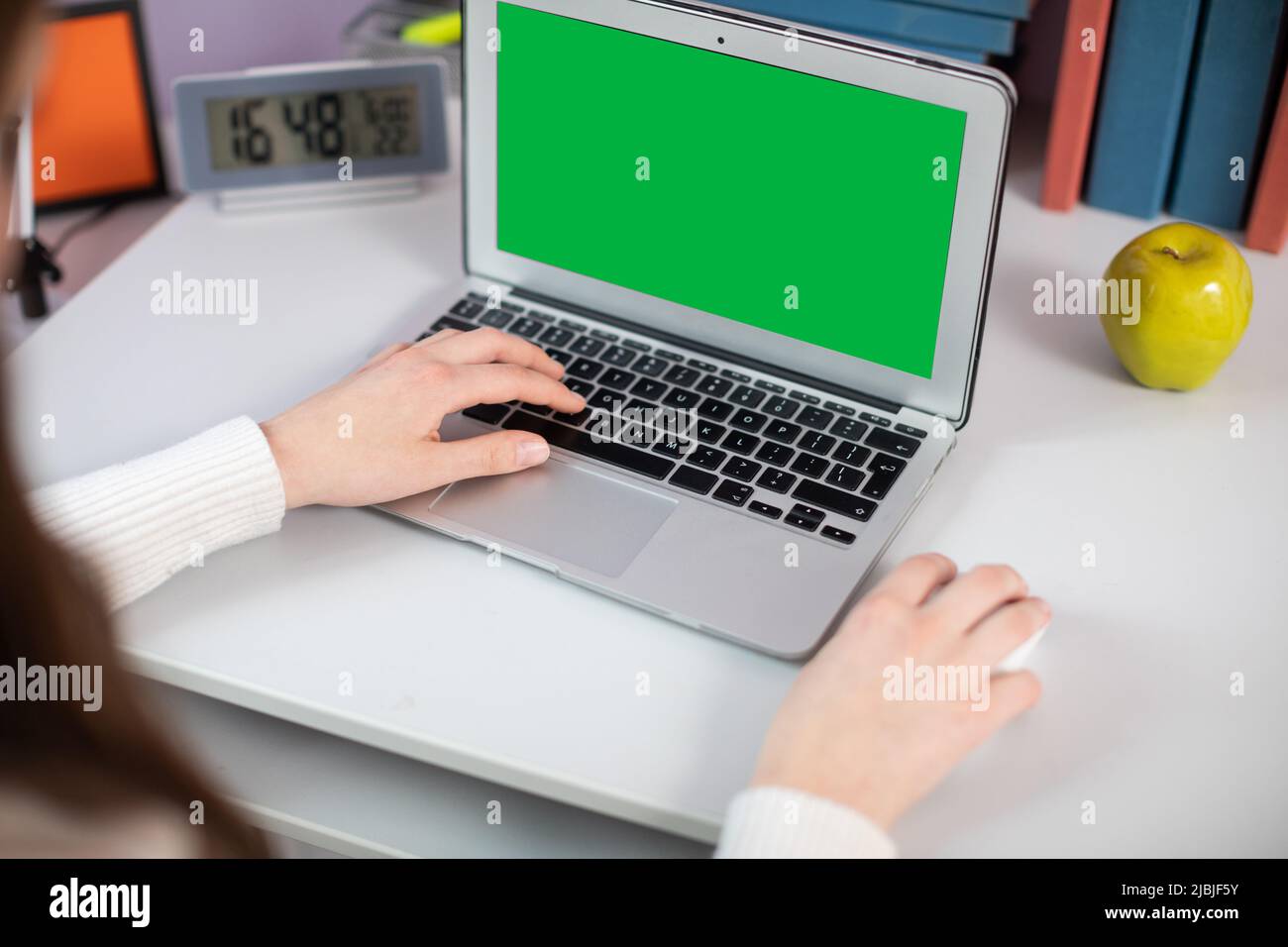 Écran vert. La fille tape sur le clavier avec sa main gauche et actionne la souris avec sa main droite. Banque D'Images