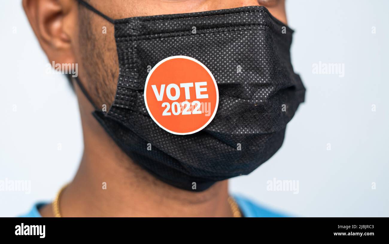 Focus sur le masque, gros plan de la jeune mna portant le vote 2022 autocollant sur le masque médical - concept de 2022 élections pendant le coronavirus ou le covid-19 Banque D'Images