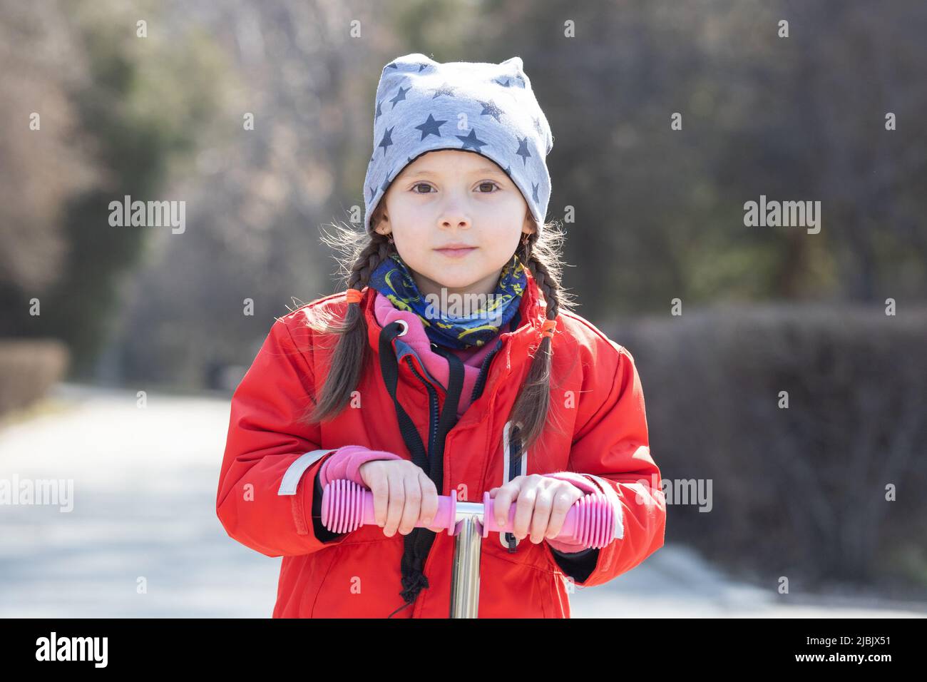 Portrait d'une fille de 5 -7 ans de race blanche sur un scooter dans un parc printanier Banque D'Images