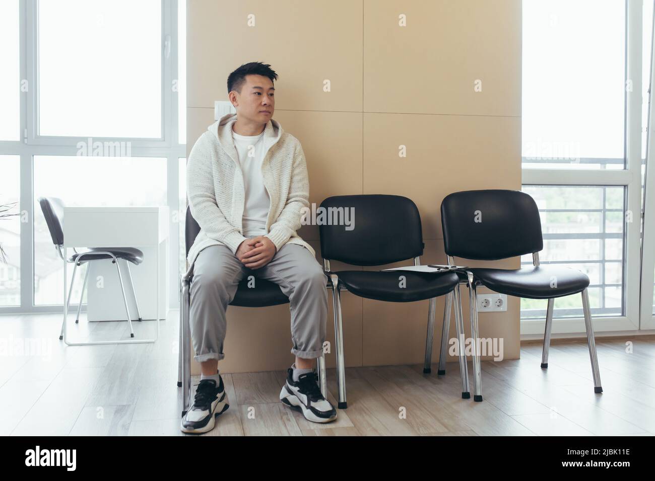 jeune asiatique attendant une entrevue ou une réunion dans le couloir de la salle d'attente. Étudiant ou participant à la réception pour examen ou emploi Banque D'Images
