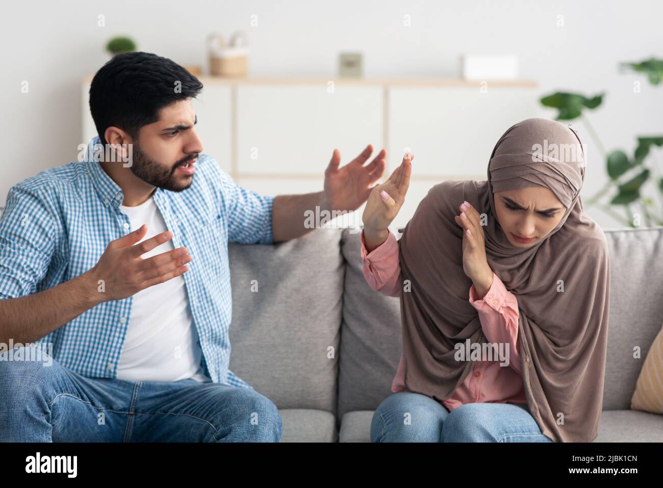 Un mari islamique fou criant à sa femme dans le hijab at Home Banque D'Images