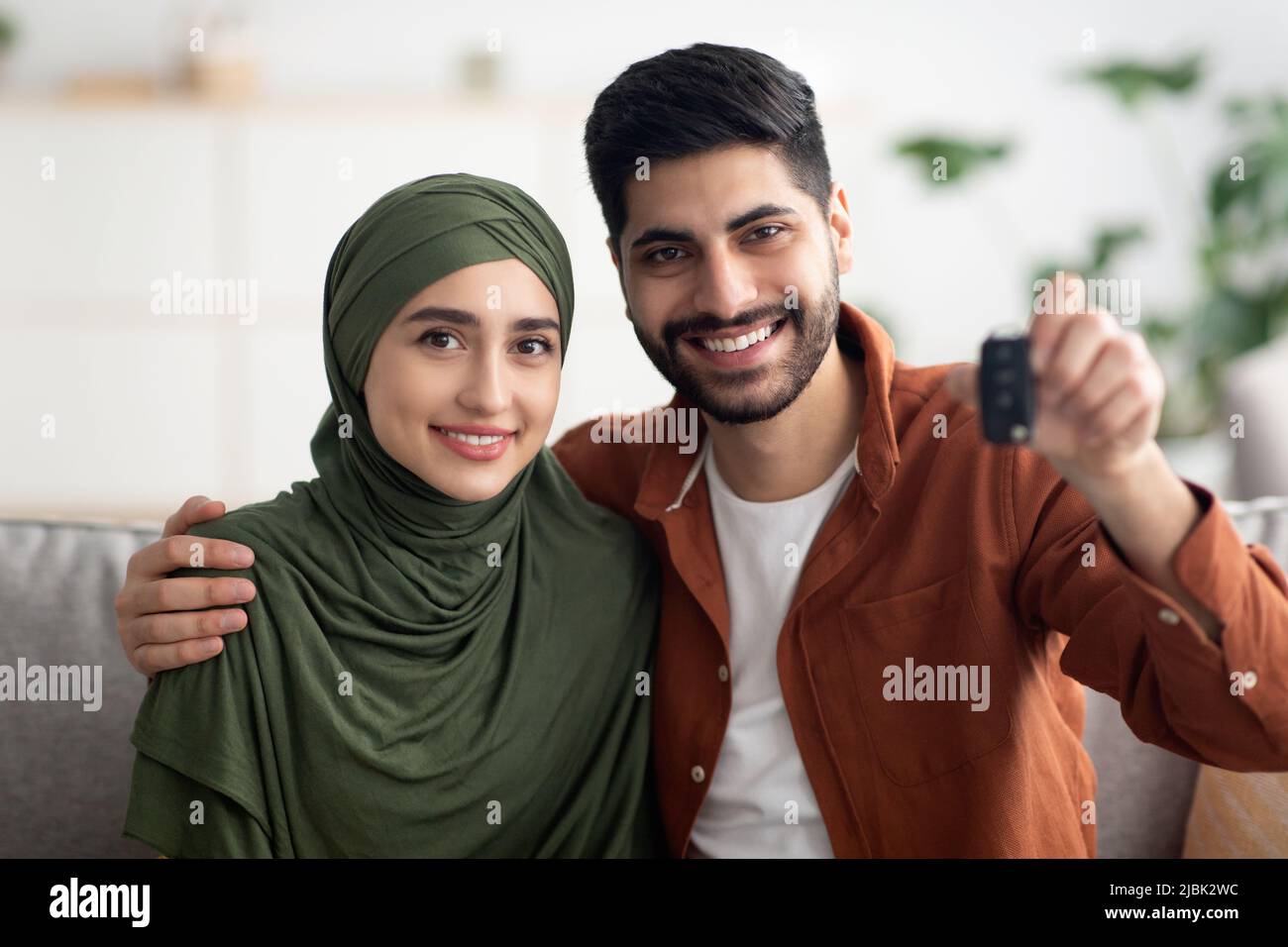 Couple musulman joyeux montrant une nouvelle clé de voiture assise à la maison Banque D'Images