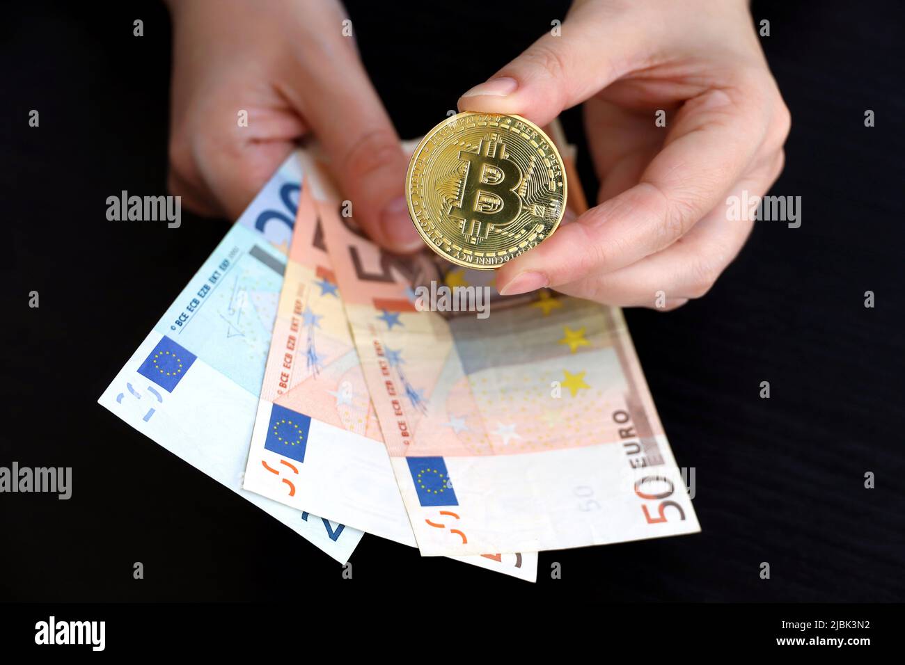 Bitcoin et billets en euros entre les mains des femmes sur fond sombre. Monnaie électronique décentralisée, crypto-monnaie Banque D'Images