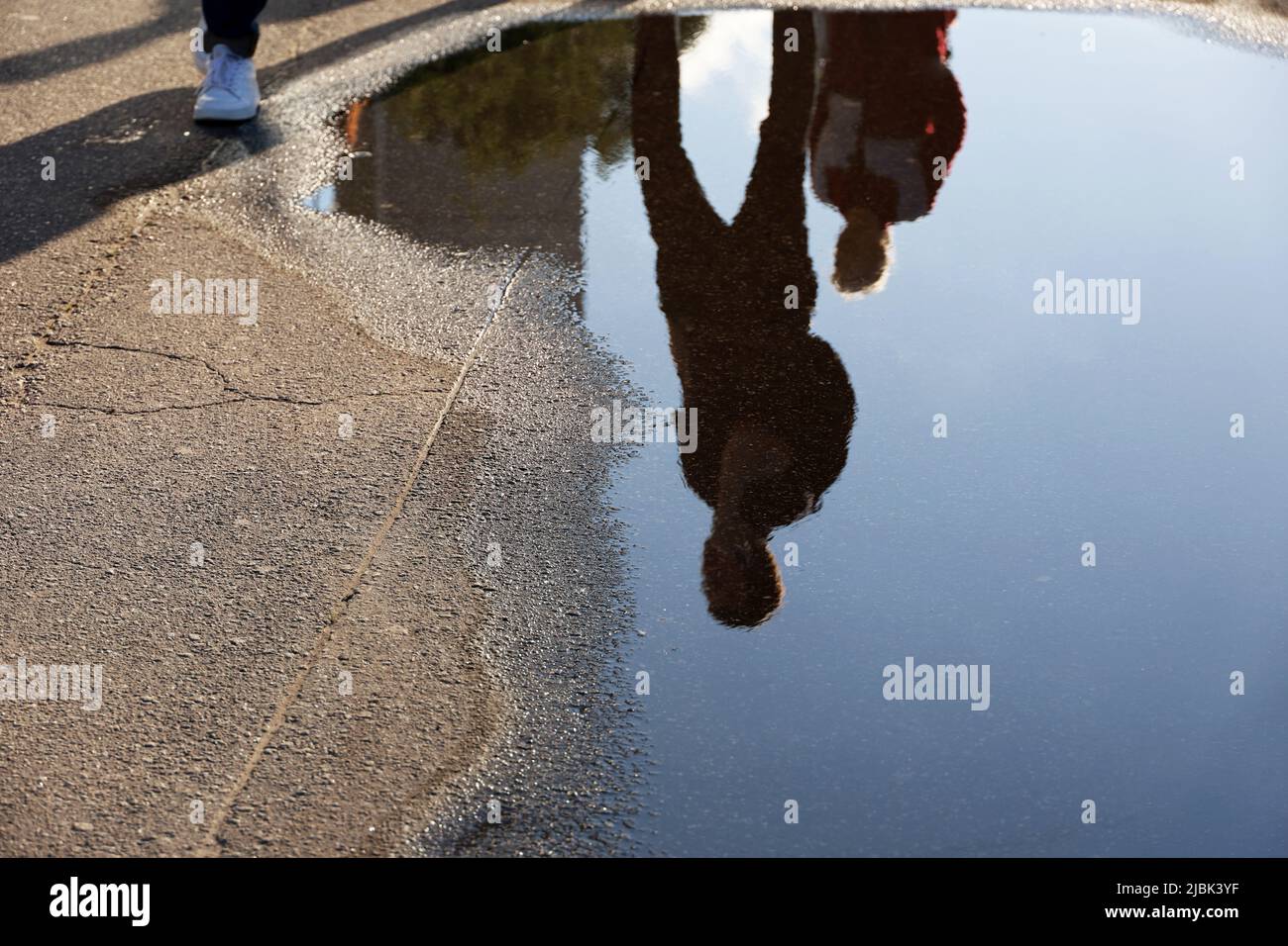 Une vue défocace pour les personnes qui réfléchissement dans une rue. Pluie en ville d'été, asphalte humide Banque D'Images