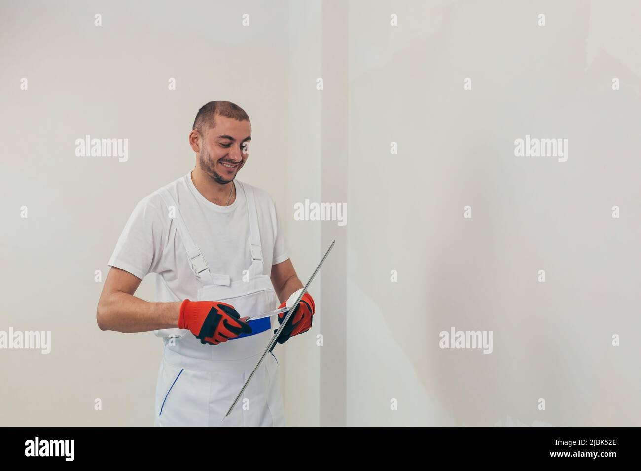 Un ouvrier plâtres le mur avec une spatule et applique une solution de mélange de ciment. Le réparateur pose le plâtre sur la cloison sèche Banque D'Images