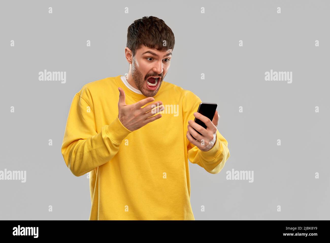 jeune homme en colère avec un smartphone Banque D'Images