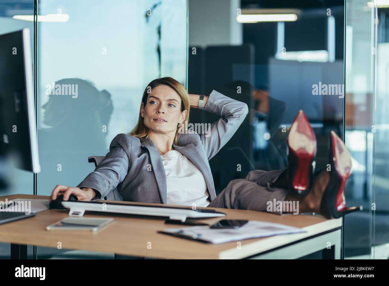 Femme directrice se reposant et rêvant au travail, femme d'affaires jetant ses mains derrière sa tête et les pieds sur la table, se reposant sur la journée de travail Banque D'Images