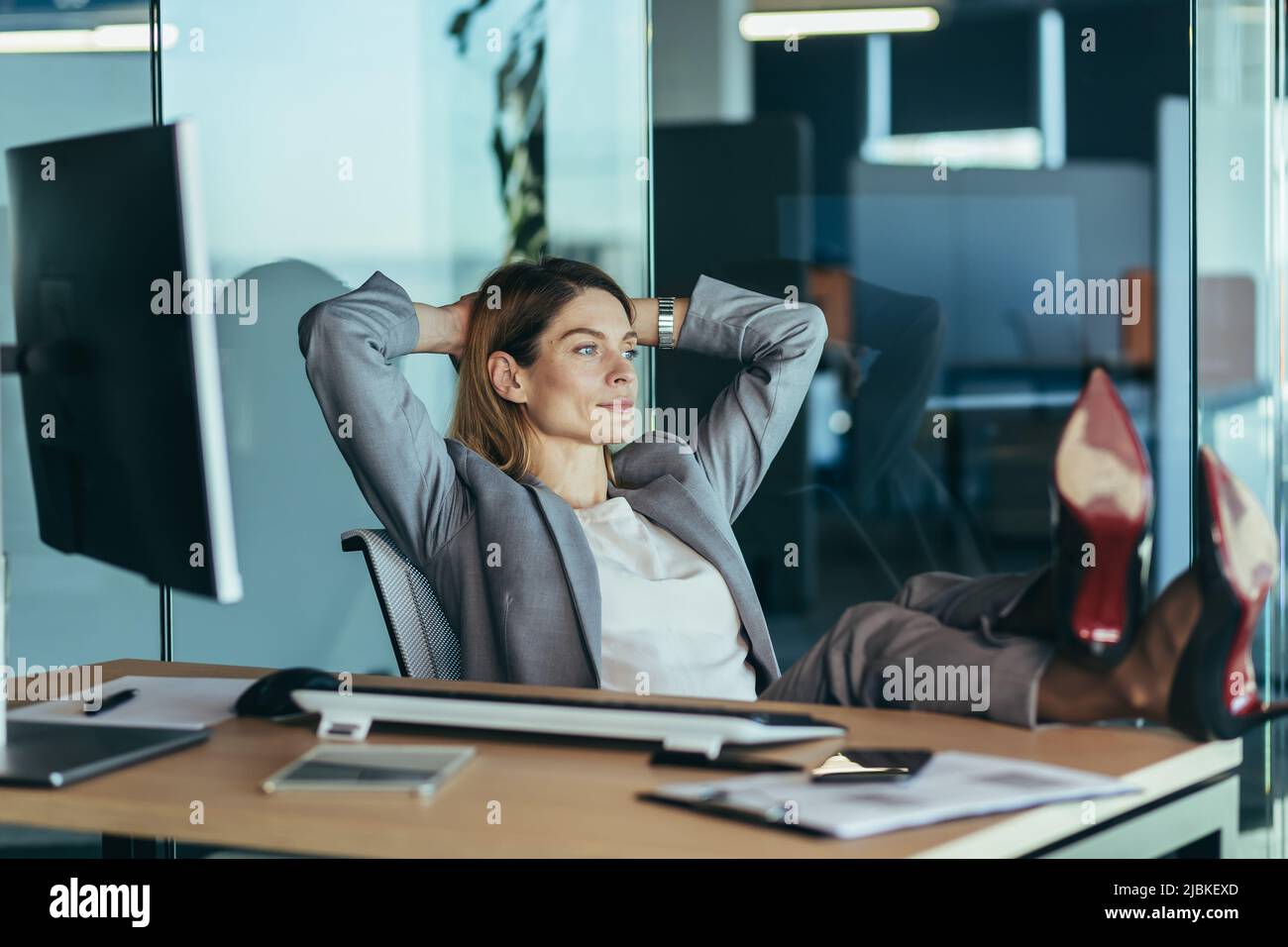 Femme directrice se reposant et rêvant au travail, femme d'affaires jetant ses mains derrière sa tête et les pieds sur la table, se reposant sur la journée de travail Banque D'Images