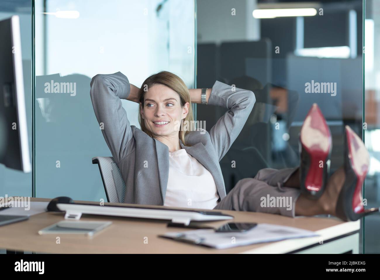 Femme directrice se reposant et rêvant au travail, femme d'affaires jetant ses mains derrière sa tête et les pieds sur la table, se reposant sur la journée de travail Banque D'Images