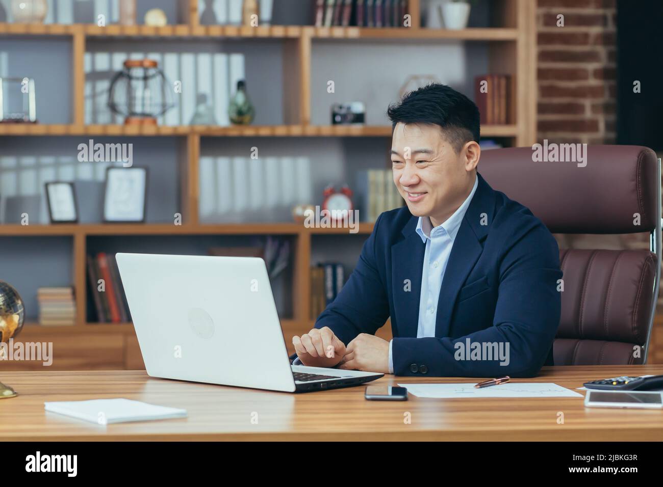 Jeune homme d'asie beau, homme d'affaires, avocat, directeur parlant sur un appel vidéo à partir d'un ordinateur portable dans le bureau, tient une réunion, consultation, discussion Banque D'Images