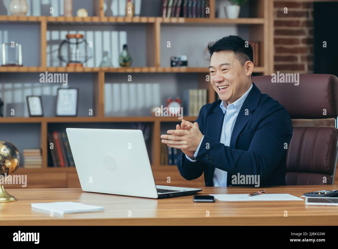 Jeune homme d'asie beau, homme d'affaires, avocat, directeur parlant sur un appel vidéo à partir d'un ordinateur portable dans le bureau, tient une réunion, consultation, discussion Banque D'Images