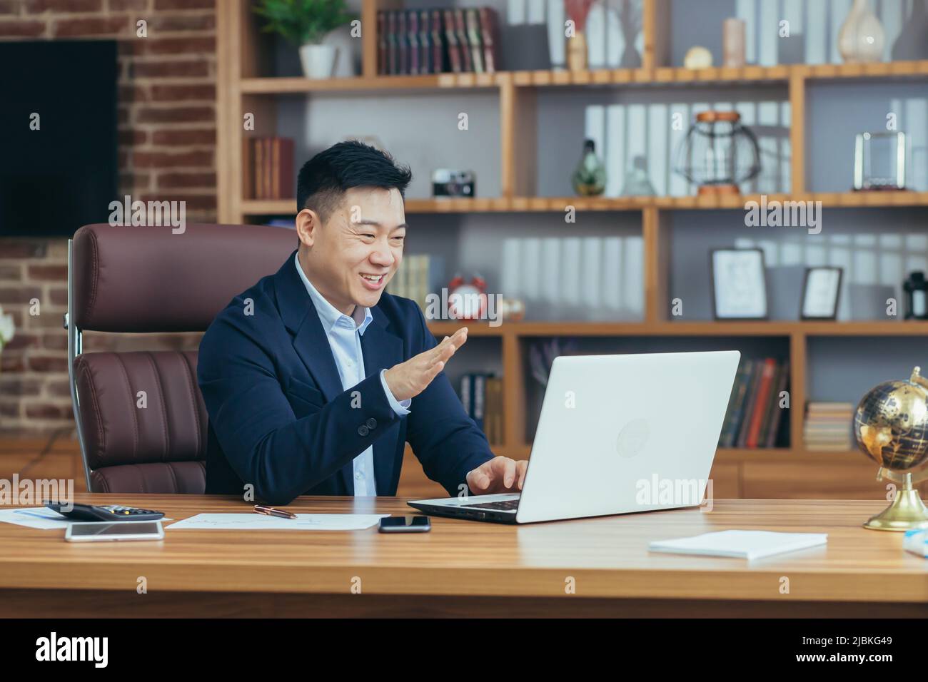 Jeune homme d'asie beau, homme d'affaires, avocat, directeur parlant sur un appel vidéo à partir d'un ordinateur portable dans le bureau, tient une réunion, consultation, discussion Banque D'Images