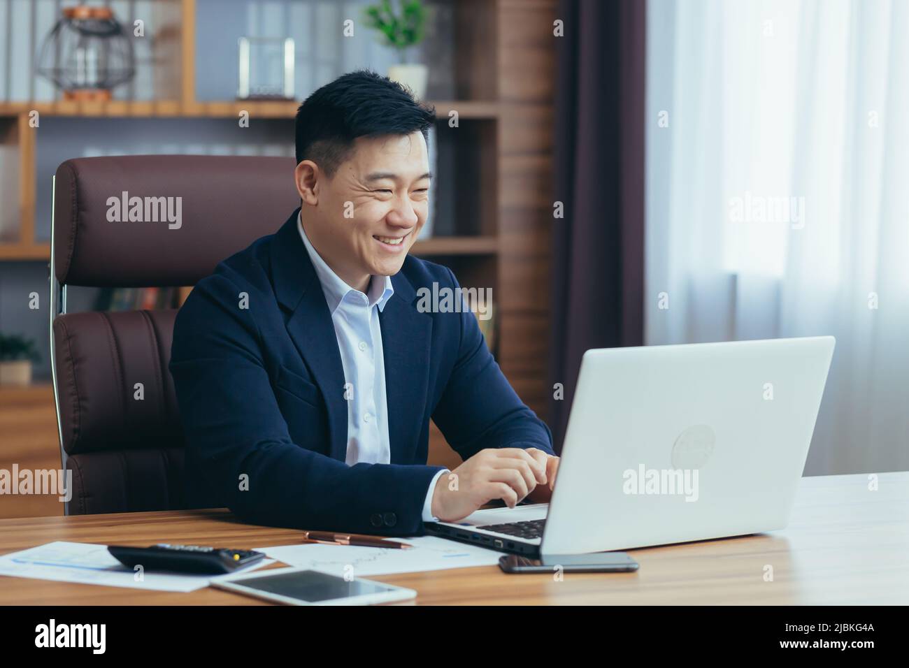 Jeune homme d'asie beau, homme d'affaires, avocat, directeur parlant sur un appel vidéo à partir d'un ordinateur portable dans le bureau, tient une réunion, consultation, discussion Banque D'Images