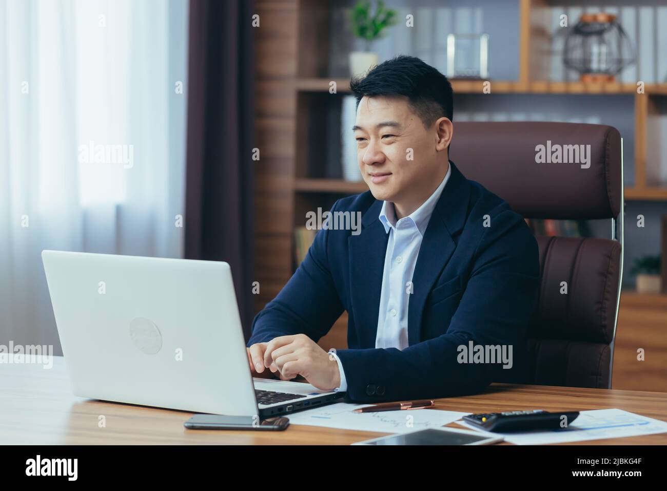 Jeune homme d'asie beau, homme d'affaires, avocat, directeur parlant sur un appel vidéo à partir d'un ordinateur portable dans le bureau, tient une réunion, consultation, discussion Banque D'Images