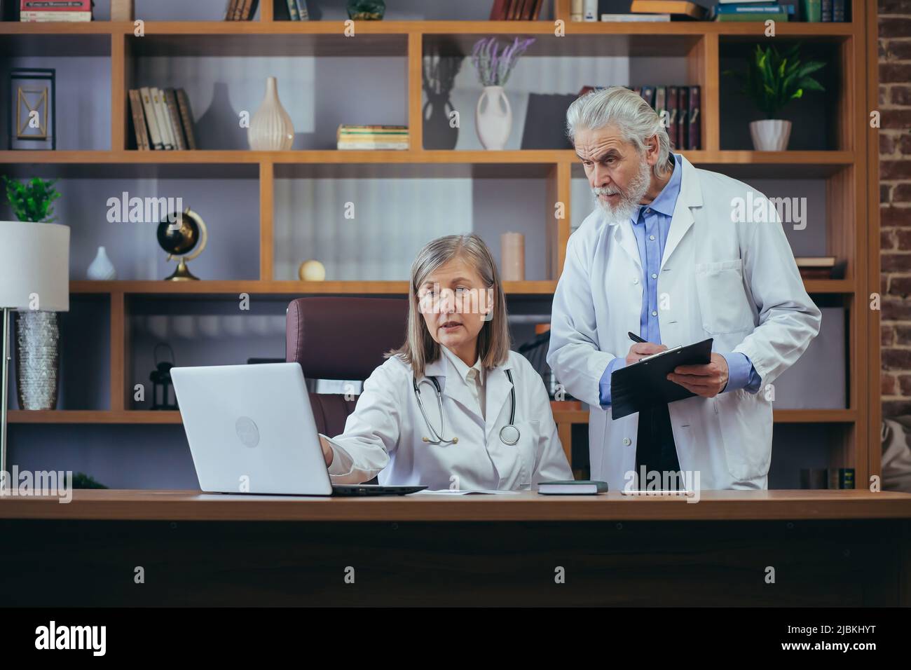 Les médecins seniors consultent et pratiquent dans le bureau classique de la clinique, discutent du diagnostic des patients Banque D'Images