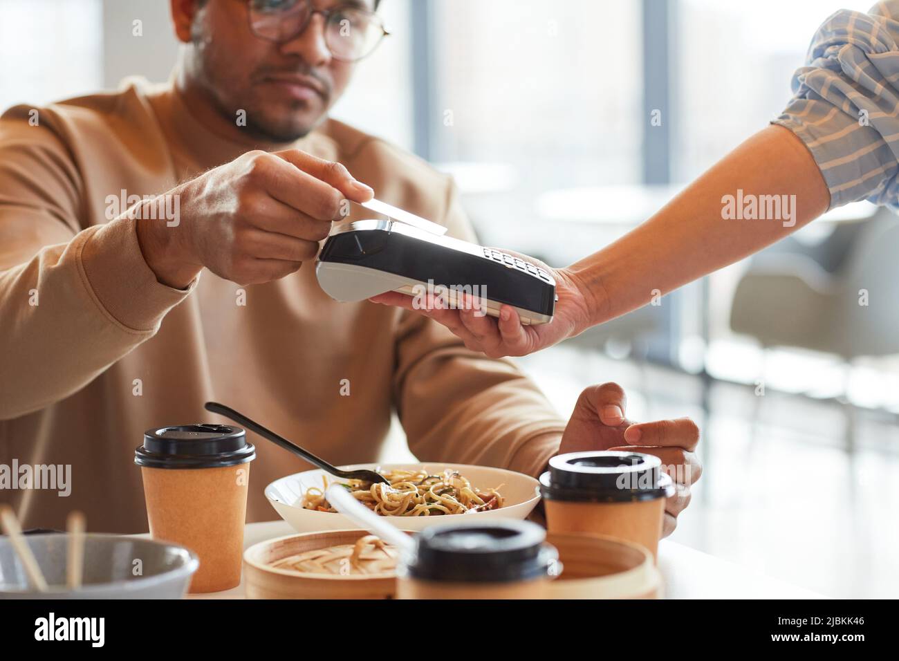 Gros plan de jeune homme payant avec carte de crédit dans le café à la cour de restauration du centre commercial, espace de copie Banque D'Images