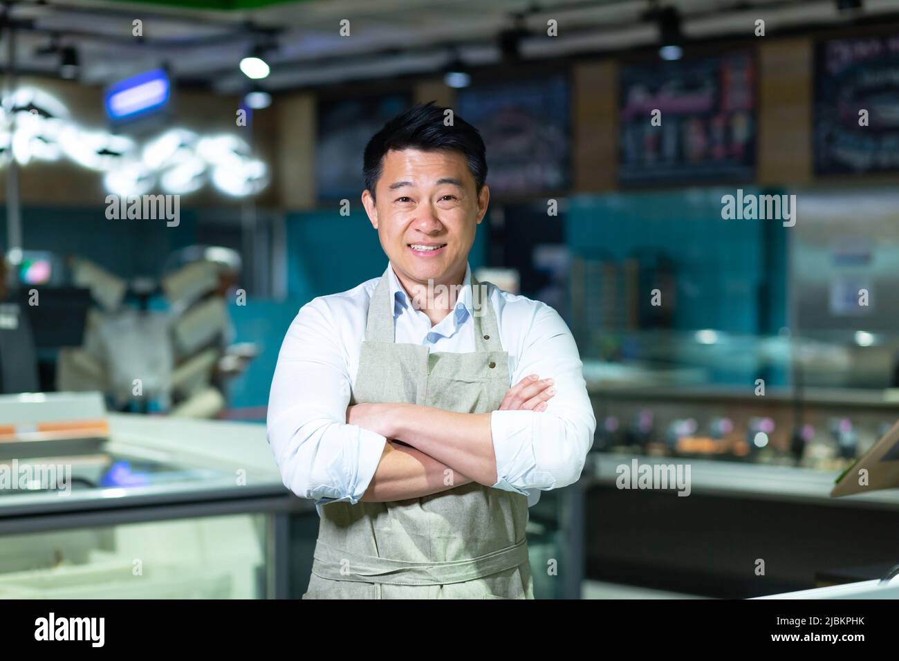 Portrait d'un vendeur asiatique de fruits de mer et d'un magasin de poissons souriant avec les bras croisés et regardant la caméra Banque D'Images