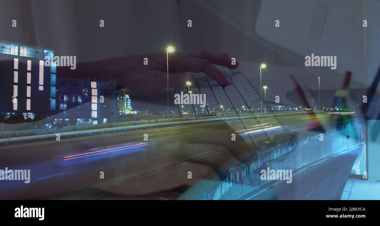 Image des mains qui travaillent sur un ordinateur portable et qui ont accéléré la circulation en ville la nuit Banque D'Images