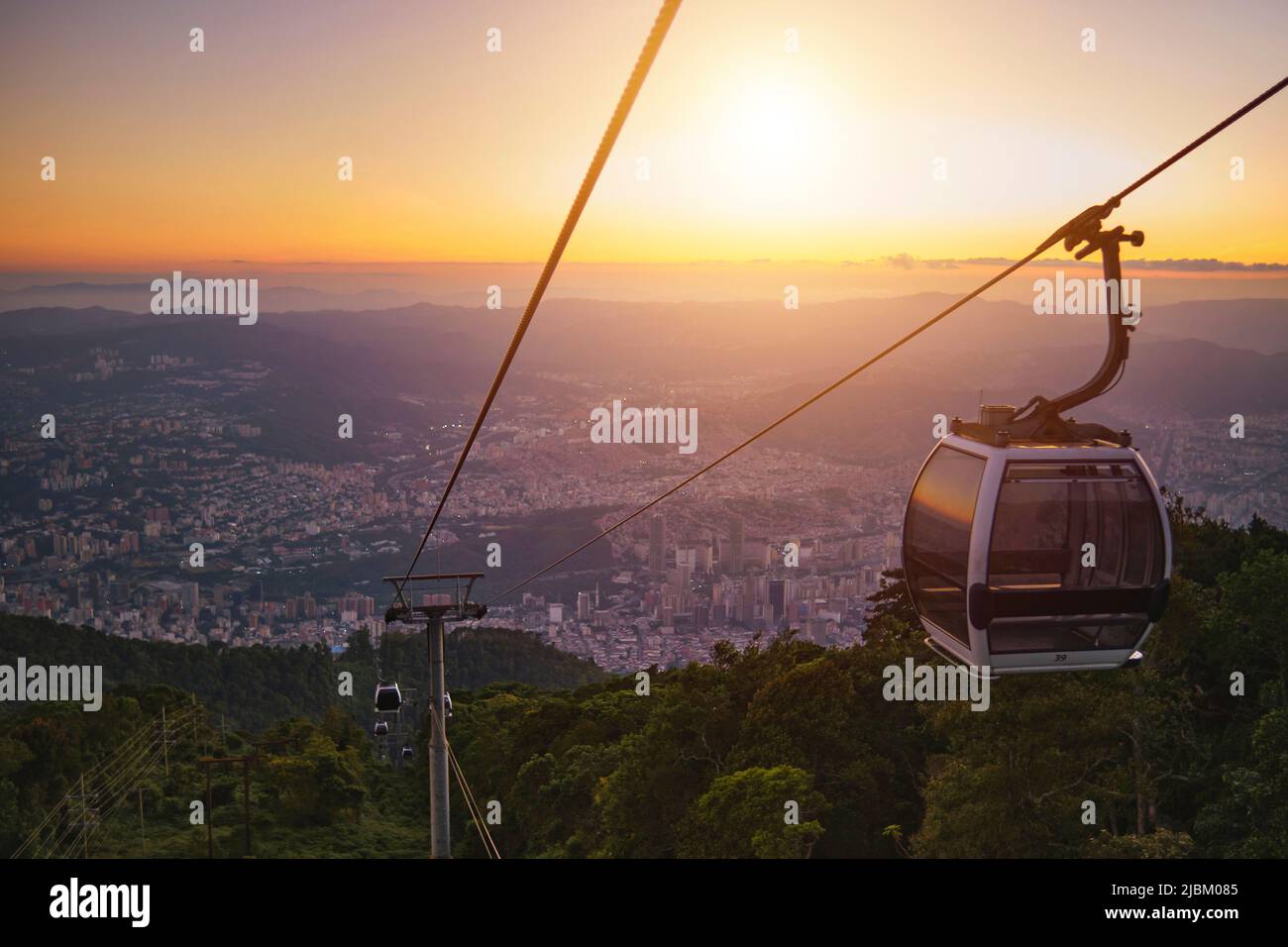 Cabines modulaires téléphérique contre le ciel lumineux, nuages et montagnes. Téléphérique - l'un des manèges urbains populaires à Caracas. Image tonifiée. Banque D'Images