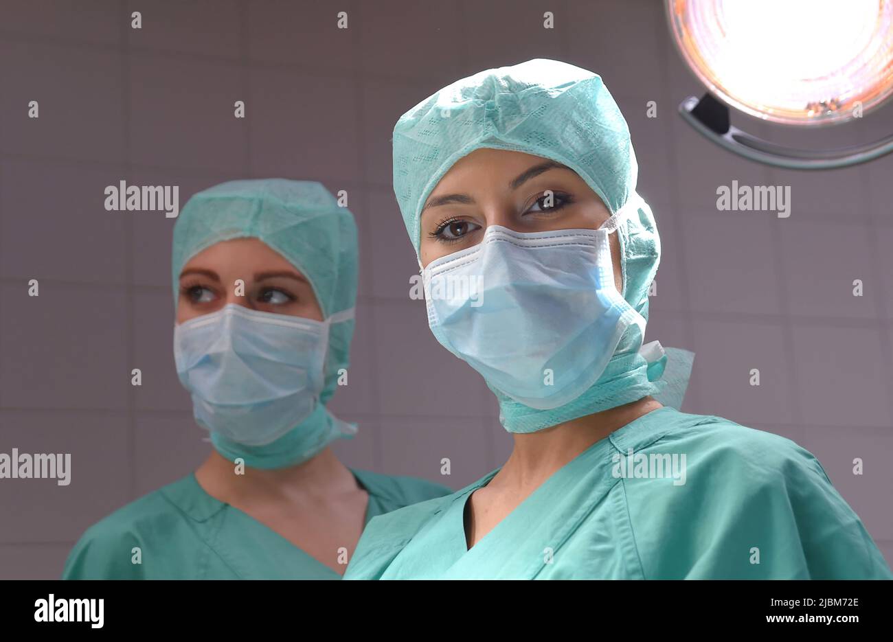 Deux jeunes femmes sont vues dans un théâtre d'opération vêtues de vêtements de chirurgie médicale. Ils portent tous les deux des masques protégés au-dessus de la bouche et du nez. Banque D'Images